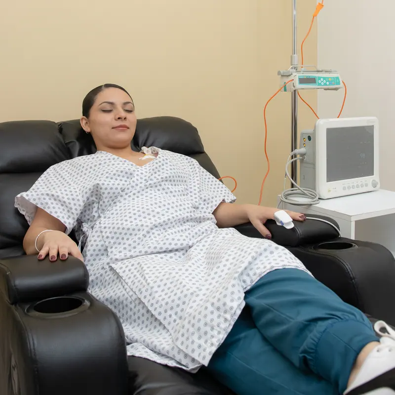 Paciente descansando con los ojos cerrados durante su sesión de infusión oncológica