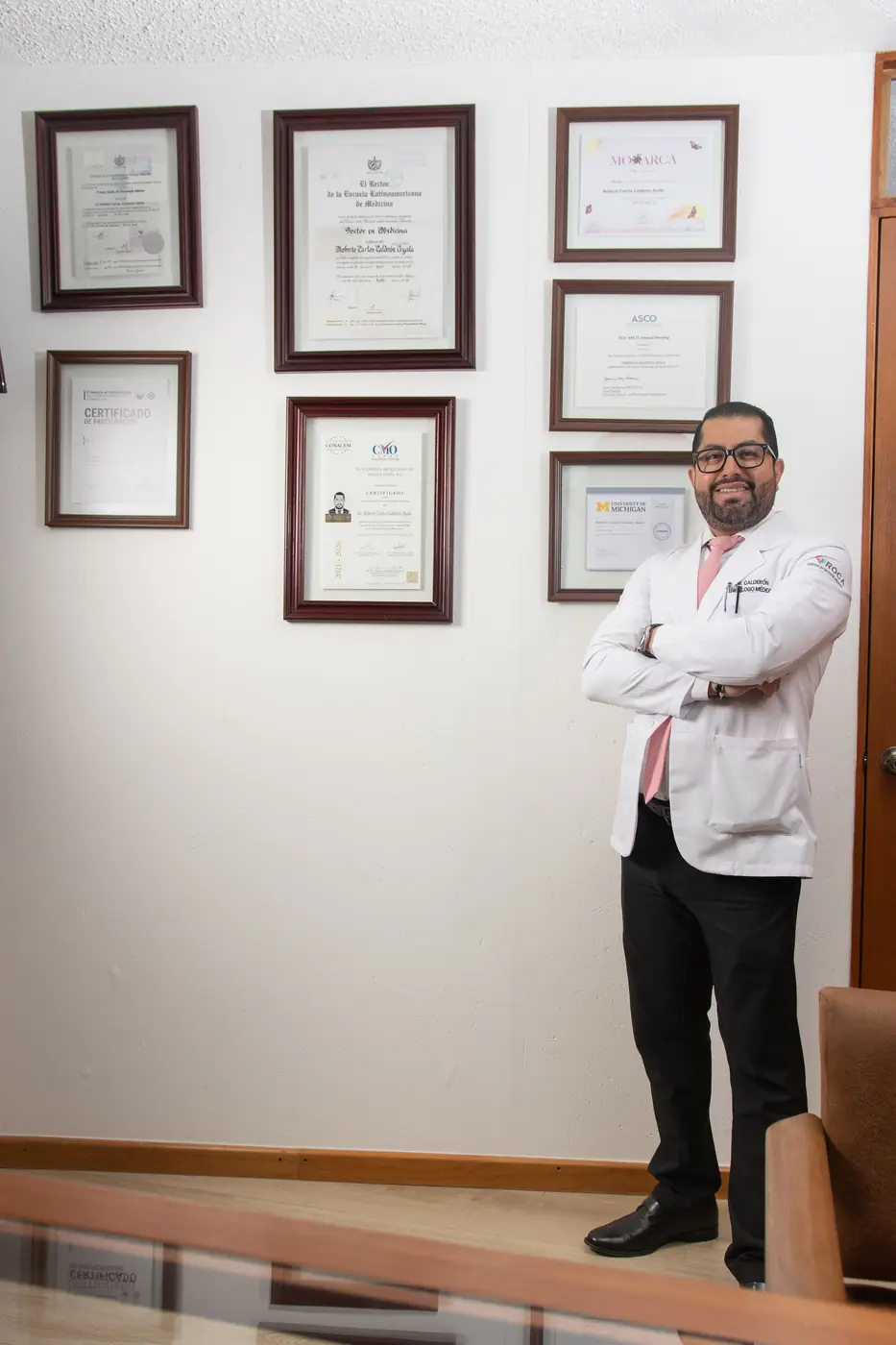 El doctor Calderón junto a su muro de certificaciones médicas nacionales e internacionales