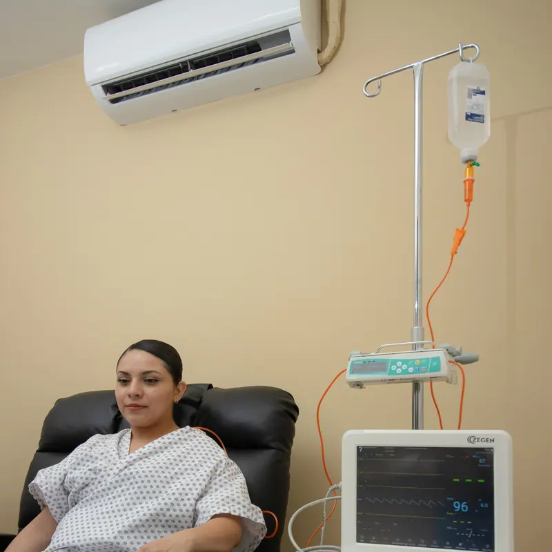 Sala de infusión privada con sillón reclinable, bomba y monitor de signos vitales