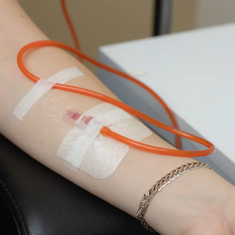 Detalle de la vía intravenosa fijada con apósito estéril en el antebrazo